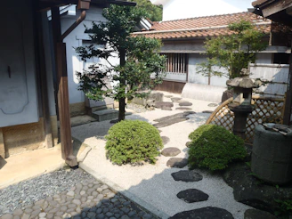 A serene Japanese garden with carefully pruned bonsai trees and a tranquil stone pathway.