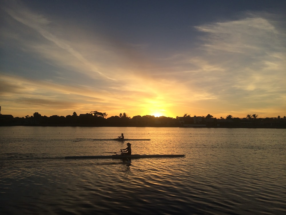 Zwei Menschen Silhouette auf einem Gewässer während der goldenen Stunde