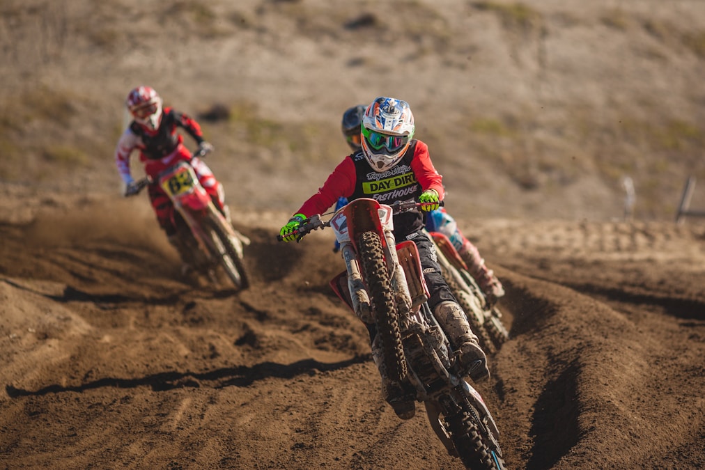 Motocross riders leaning through a dusty dirt-track corner