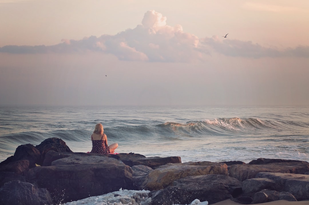 woman sitting on rock near body of water during daytime