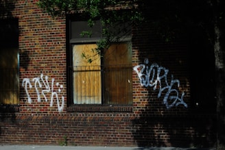 Workers removing graffiti from a brick wall as part of a community cleanup project.