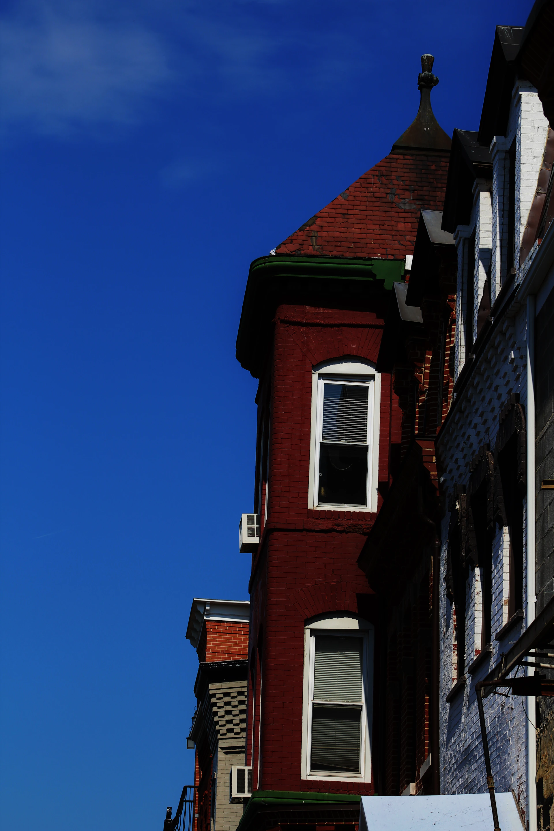 A row of smooth coping stones and string courses lining a classic brick facade under a clear blue sky.