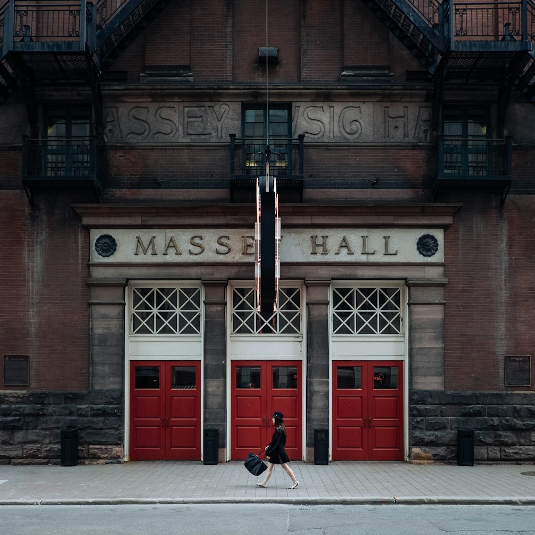 woman walking on street near red Masse Hall during daytime