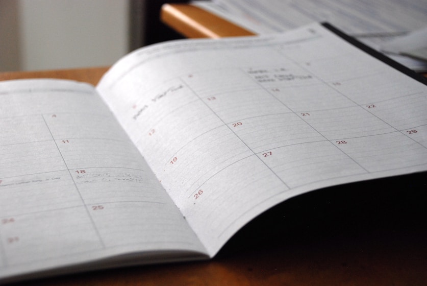 Desk calendar and pen beside morning light on a table