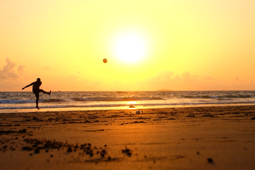 man kicking ball on seashore