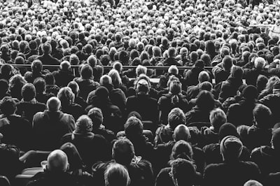 grayscale photo of people sitting on chair crowd teams background