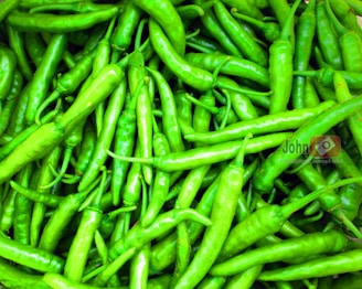 Close-up of vibrant fresh Anaheim, jalapeño, and serrano chiles arranged on a rustic wooden table.