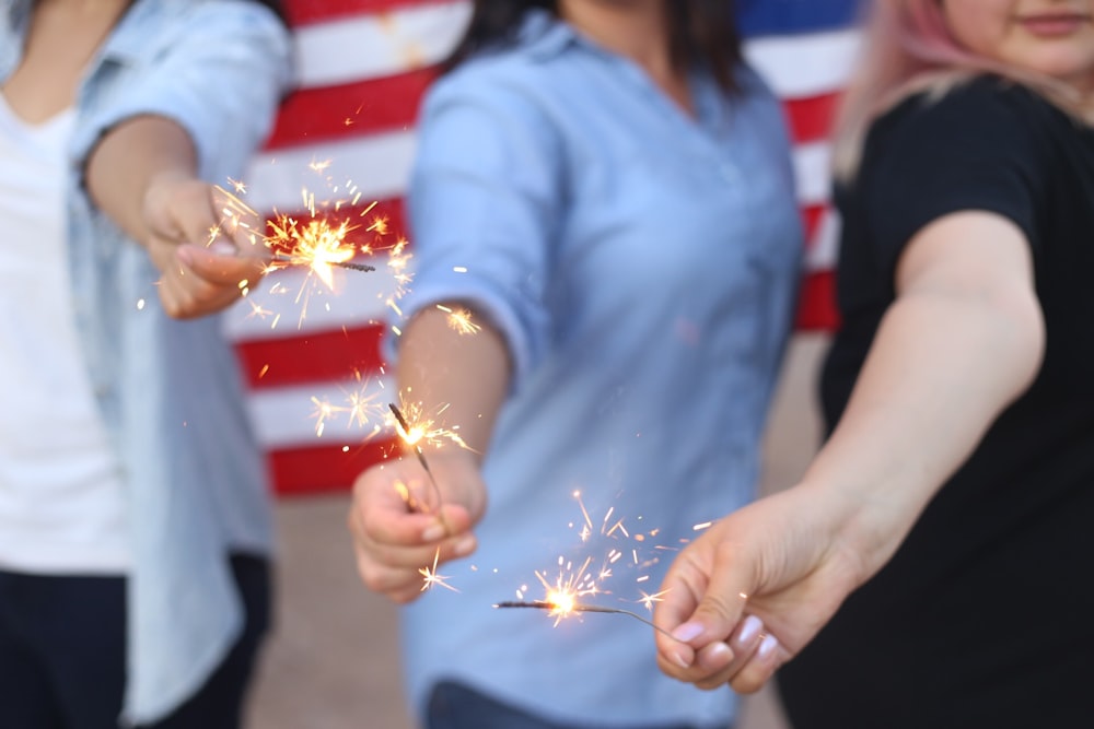 three person holding sparklers