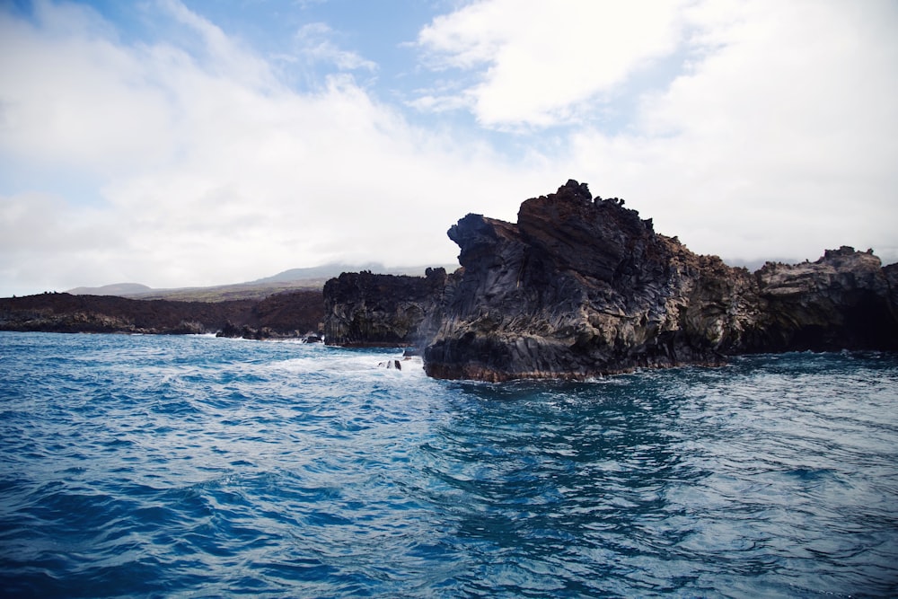 rock in ocean under white sky