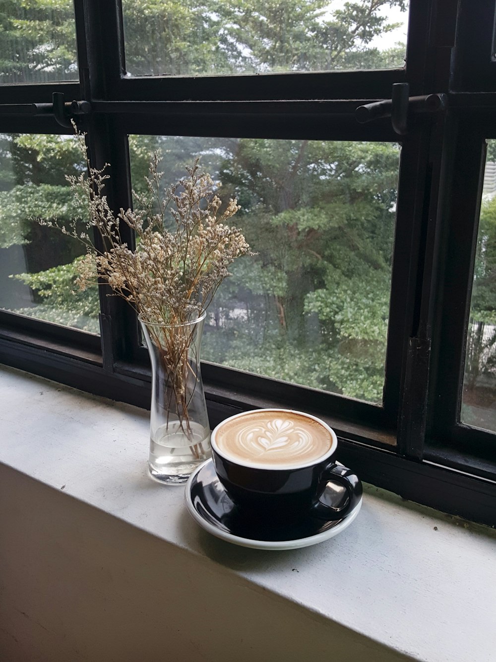 black ceramic coffee mug on window