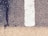 A close-up view of a road surface featuring a white painted line dividing the darker textured asphalt on the right from a lighter-colored strip below. A noticeable crack with a dark stain runs vertically through the surface.