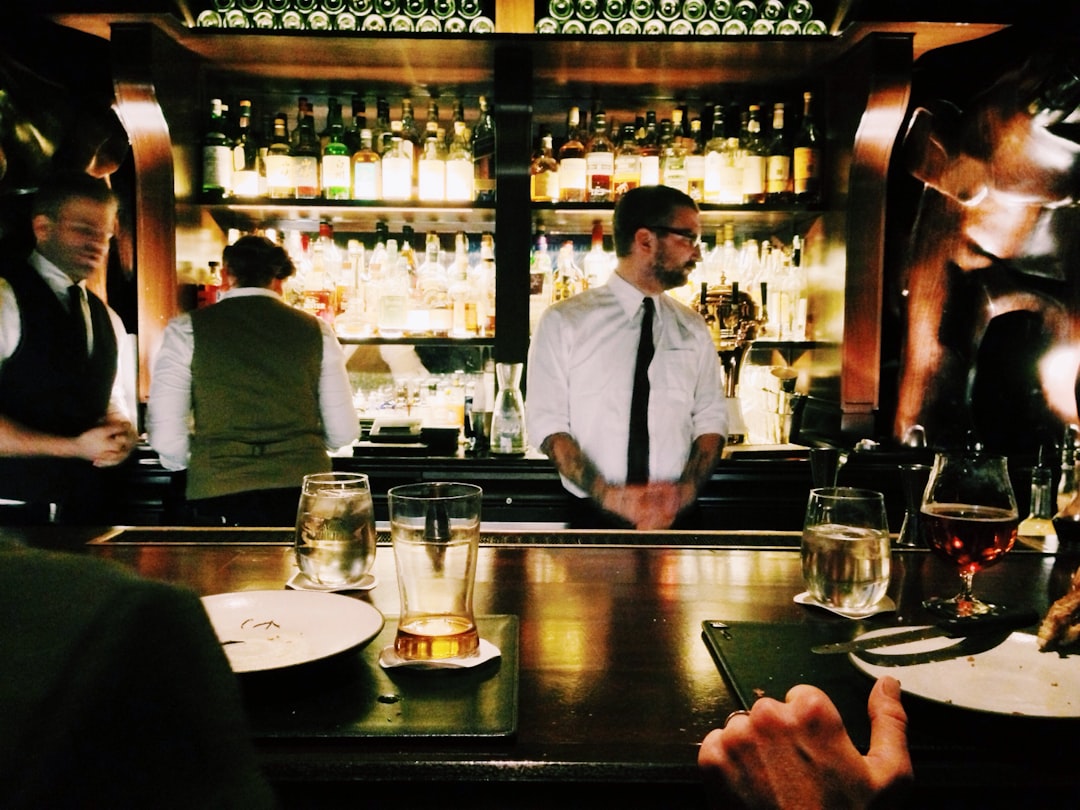 bartender standing beside table, Bartenders serving in a bar