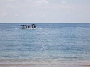 A boat approaching a group of whales in clear ocean waters under a bright sky.