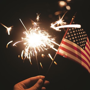 time lapse photography of sparkler and U.S.A flag let