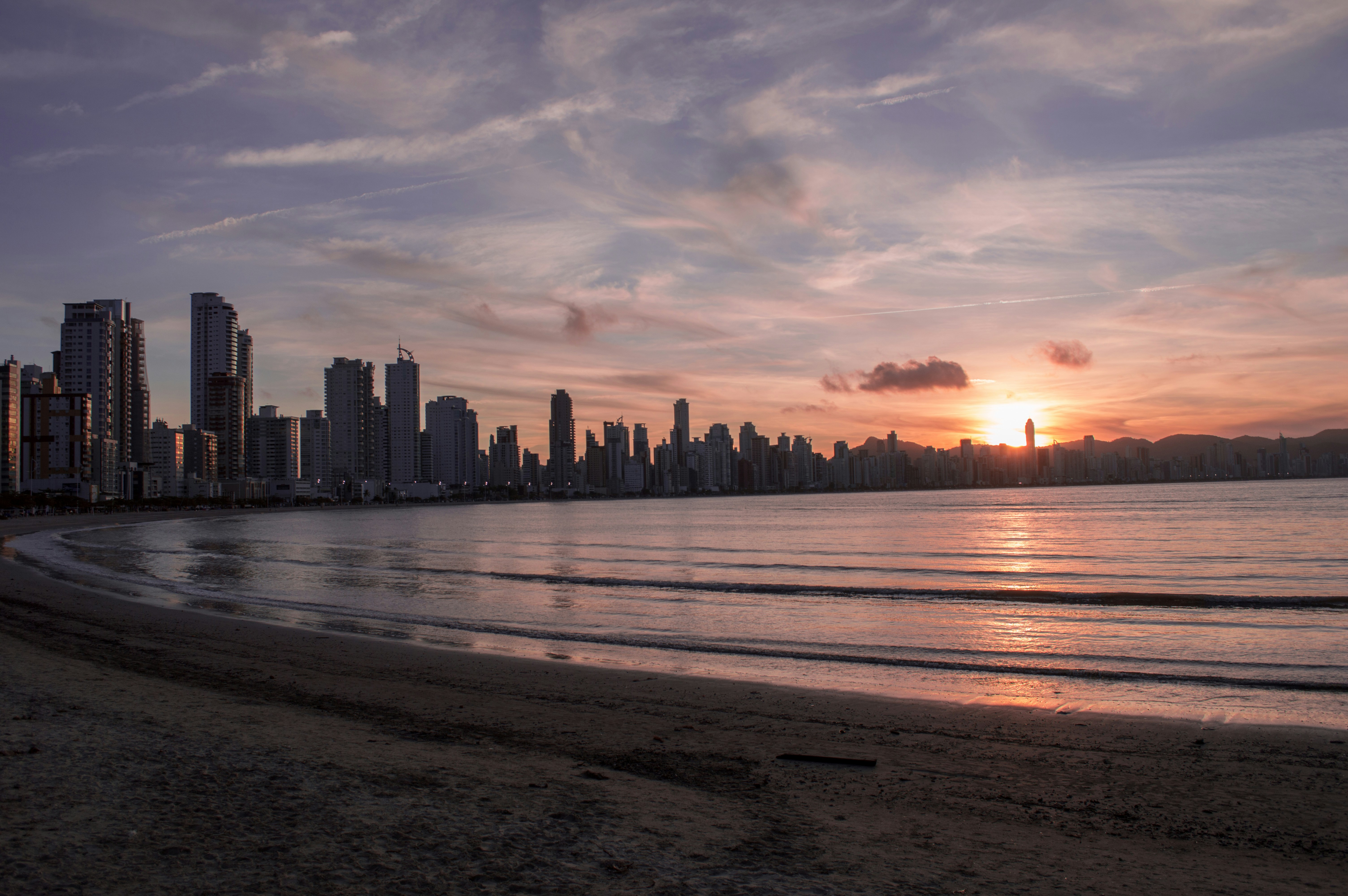 city buildings near ocean water during sunset, 