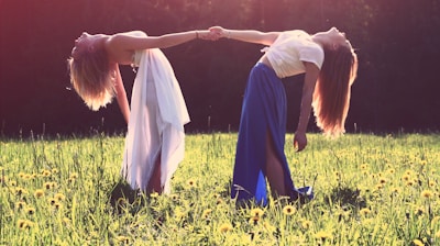 two women bending while holding hands