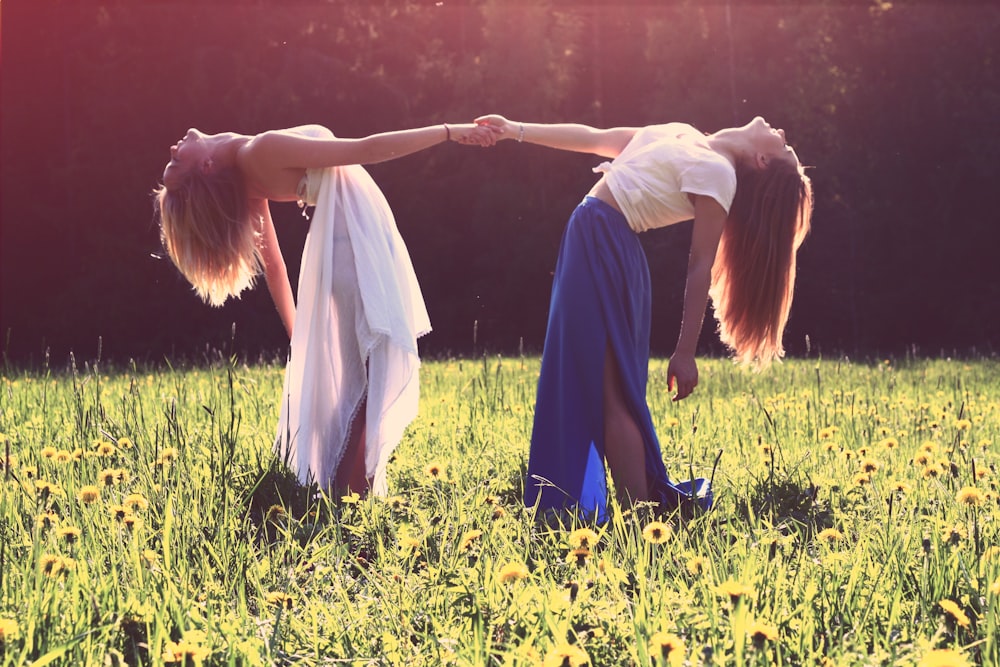 two women bending while holding hands, feminine energy