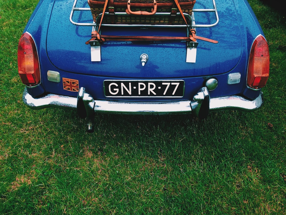 selective photo of blue car on green grass field during daytime