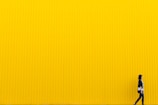 woman wearing black top standing near yellow wall