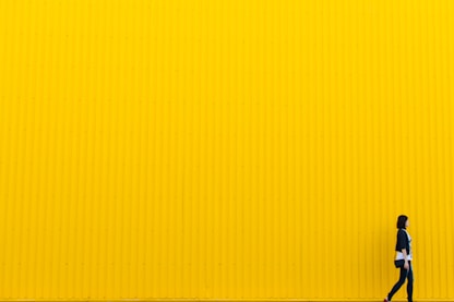 woman wearing black top standing near yellow wall