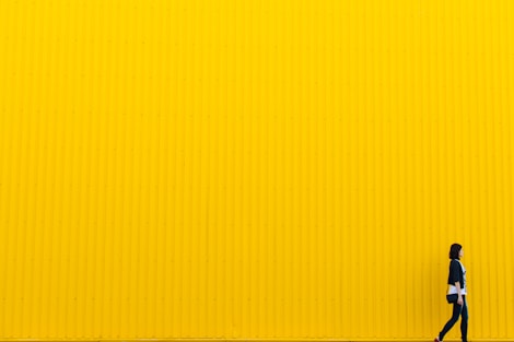 woman wearing black top standing near yellow wall