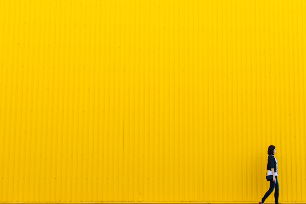 woman wearing black top standing near yellow wall