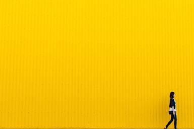 negative space for photo composition,how to photograph yuliia kutsaieva near yellow wall of supermarket; woman wearing black top standing near yellow wall