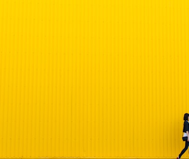 woman wearing black top standing near yellow wall