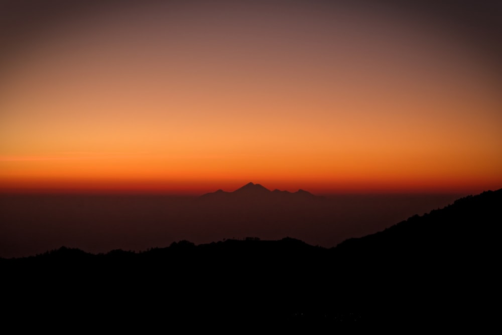 Silhouettenfotografie von Bergen bei Sonnenuntergang