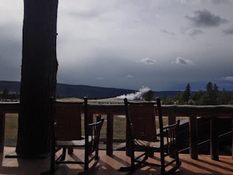 A cozy lodge porch with rocking chairs overlooking rolling hills at sunset.