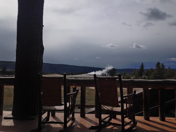 A cozy lodge porch with rocking chairs overlooking rolling hills at sunset.