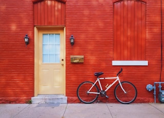 white bicycle parked beside wall