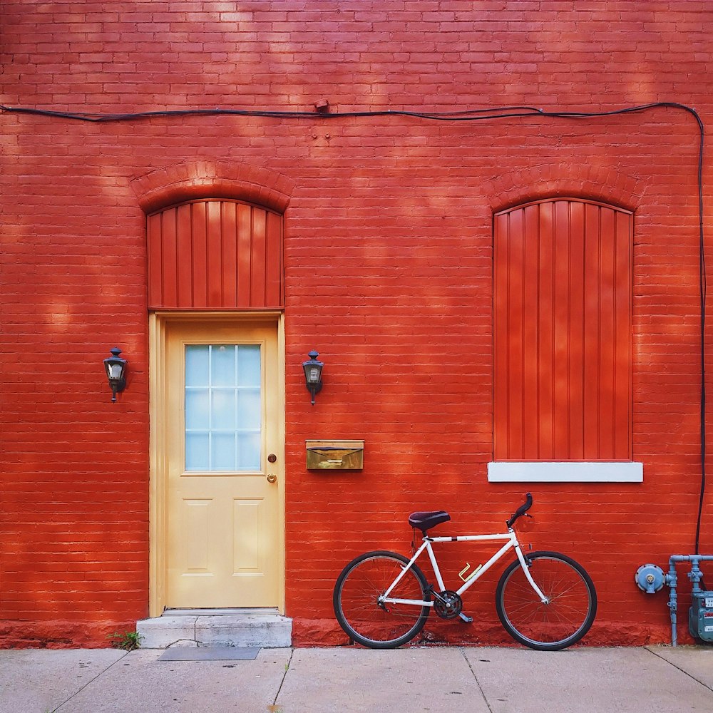 white bicycle parked beside wall