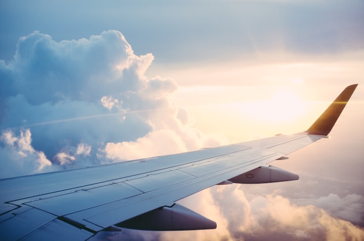 An airplane wing above the clouds at golden hour