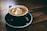 white and black ceramic mug filled with brown latte on round black ceramic saucer