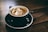 white and black ceramic mug filled with brown latte on round black ceramic saucer