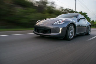 Low-angle shot of a performance car speeding past a highway camera, highlighting asphalt textures and heat haze.