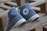 A pair of worn blue Converse All Star sneakers are placed on a wooden pallet. The shoes are tilted sideways showing the iconic logo. The surface appears rustic, adding a vintage feel.