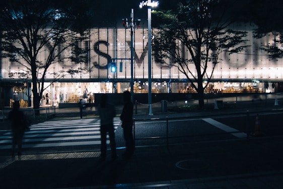 A glowing, modern lighted sign mounted on a bustling storefront at dusk.