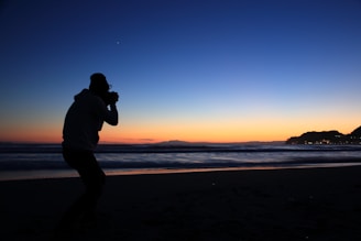 Solo traveler taking photos of a stunning sunset on a beach getaway.