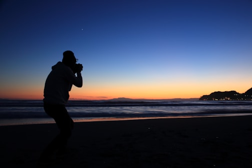 Solo traveler taking photos of a stunning sunset on a beach getaway.