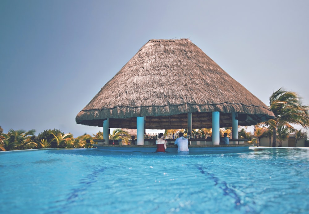 homme et femme dans la piscine bleue sous le chalet à la journée