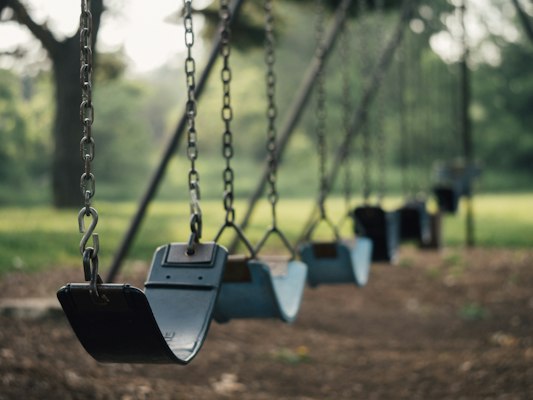 Columpios vacíos en un parque, evocando la infancia y la ausencia