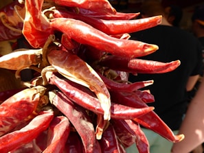Bright red chili peppers drying in the sun, their glossy skins catching the light.