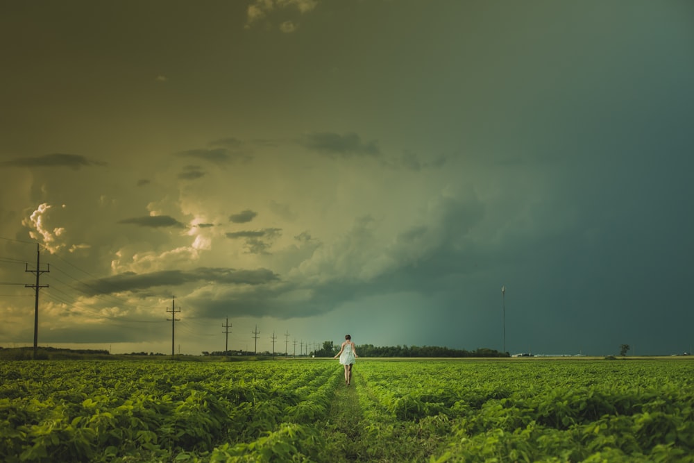 Persona caminando cerca de un poste eléctrico bajo un cielo nublado