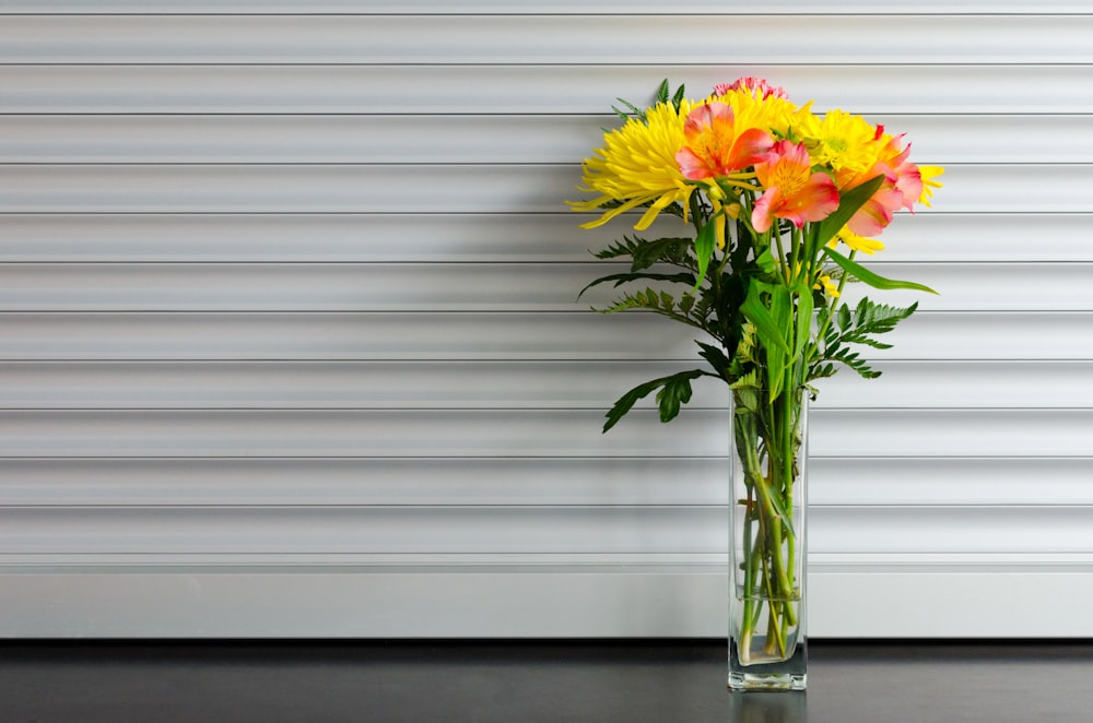 yellow and red petaled flower in clear glass vase