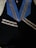 A black graduation gown with a blue stole featuring silver stripes laying on a surface.