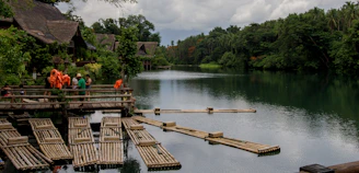 A serene riverside tribal village with artisans weaving colorful textiles under tall trees.