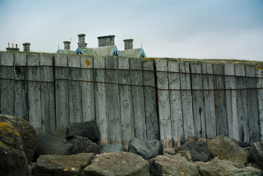 gray wooden fence on gray rocky field during daytime