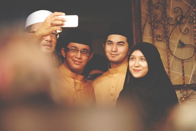 A joyful family taking a selfie in front of the Kaaba.